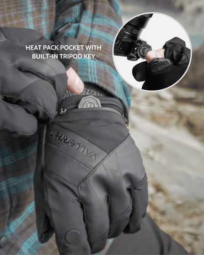 A close-up of a person wearing a black Vallerret Markhof Pro V4 insulated glove, showing the back of the hand with a built-in tripod key pocket. A circular inset shows the built-in key being inserted into the tripod socket.